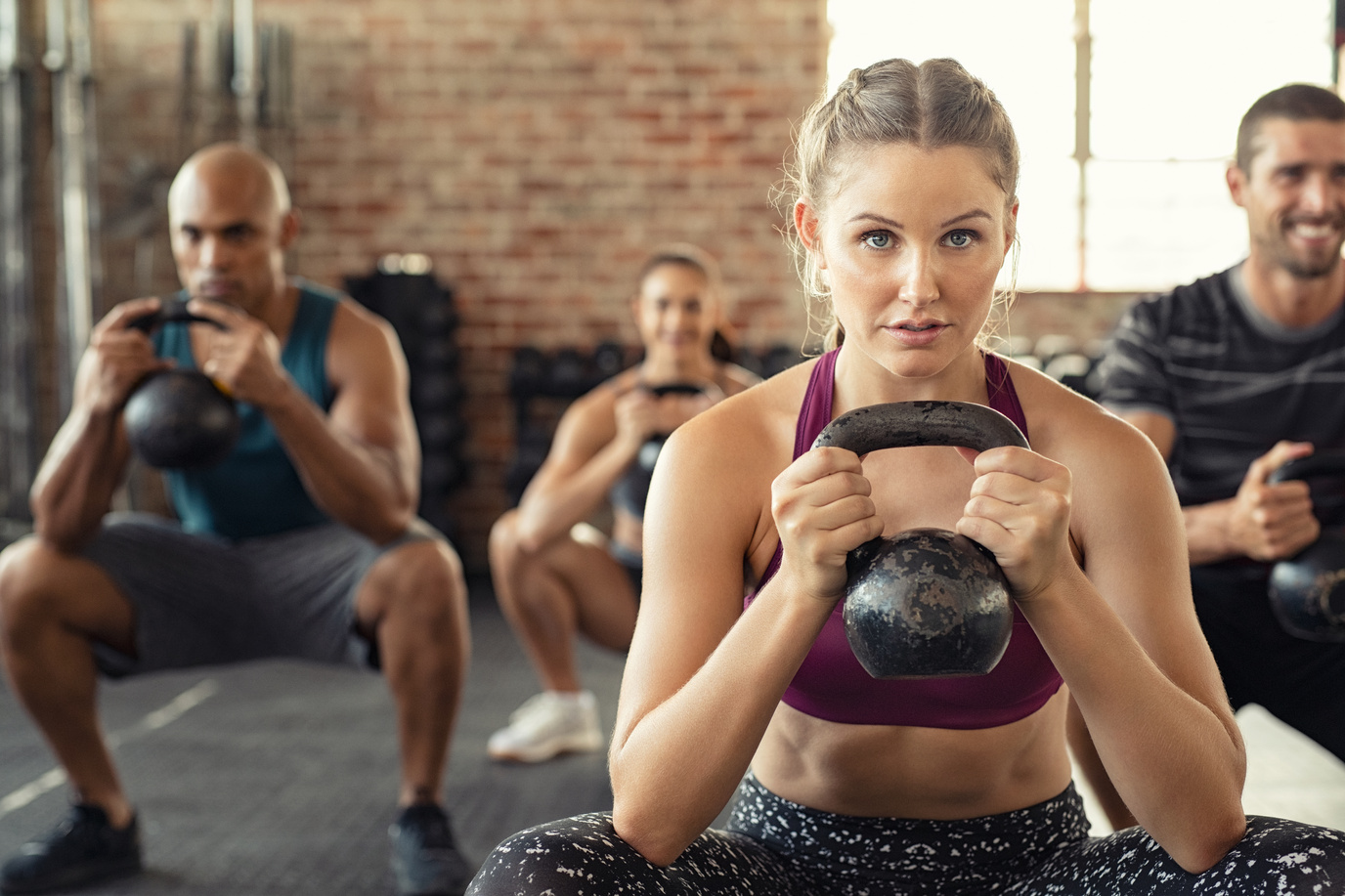 Woman Squatting with Kettle Bell at the Gym